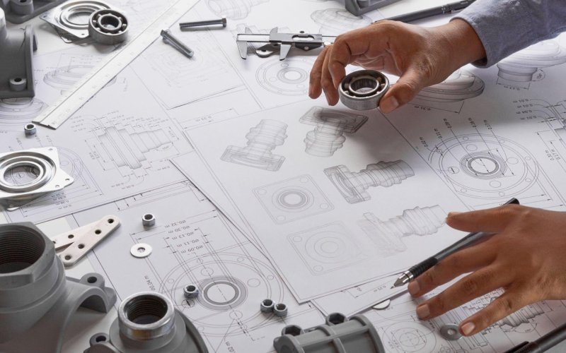 Engineer reviewing machined parts and drawing